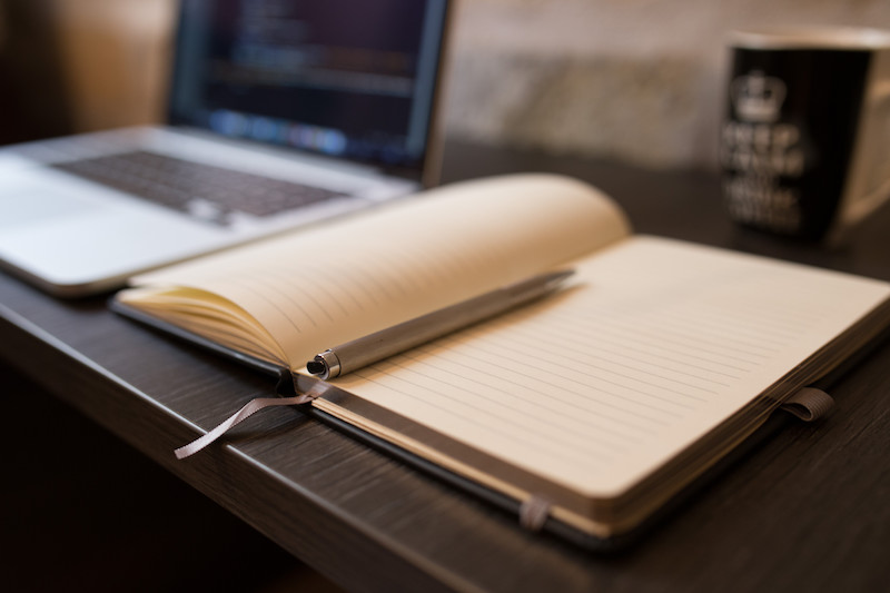 An open notebook next to a Macbook