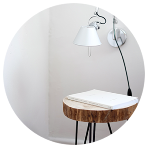 Wooden table with magazine resting on top with a lampshade above it